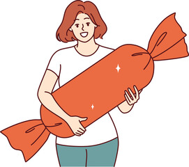 Woman holds gift with sweets in form of candy for child entering first grade or celebrating birthday. Christmas gift for children in hands of smiling girl, bought present in sweets store