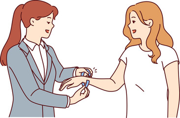 Woman administrator of nightclub puts bracelet on arm of female visitor came to closed party