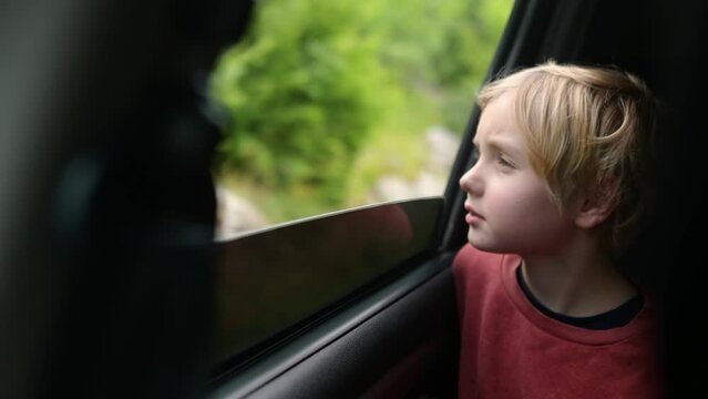 Preteen boy look out through window of car during family road trip and enjoy of pleasant expectation of happy vacation. Glad child travel with parents while holidays. Journey through the countryside