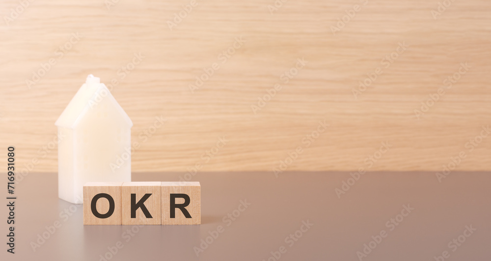 Aufkleber cubes form the word okr on a light background there is a row of cubes and a toy house in the backgro