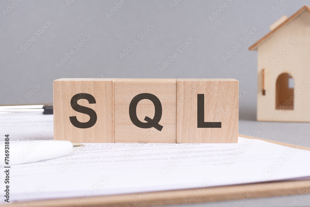Poster sql text made of wooden blocks on gray background with a small wooden model house