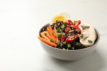 Tasty buckwheat noodles (soba) with chili pepper, egg, carrot and mushrooms on white marble table, space for text