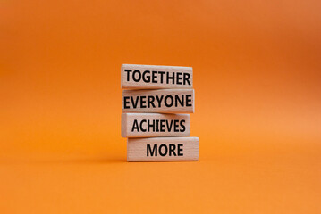 Together Everyone Achieves More symbol. Concept words Together Everyone Achieves More on wooden blocks. Beautiful orange background. Business concept. Copy space.