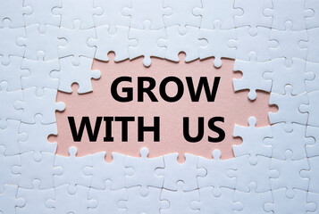 Grow with us symbol. Concept words Grow with us on white puzzle. Beautiful pink background. Business and Grow with us concept. Copy space.