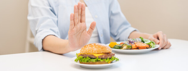 Diet concept, asian young woman hand reject eat burger, hamburger on plate, push out or deny to eat...