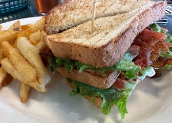 A traditional BLT sandwich with bacon, lettuce, and tomato served with french fries