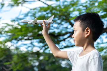 Cute Asian child playing airplane in the park outdoors Happy Asian boy holding a plane runs in a...