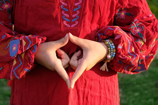 Woman on a red dress, doing meditation yoga mudra of hands, yoni symbol. female adi shakti hand gesture. spiritual, tantric practice, meditation. female energy, health concept.