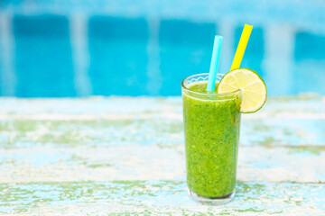 Freshly blended green fruit smoothie in glass with straw