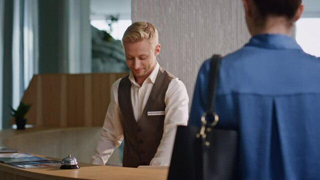 Receptionist assisting hotel guests at desk closeup. Tourist couple make payment