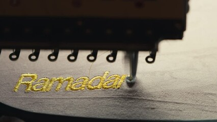 Sewing Machine Prints the word Ramadan in Golden Letters on Fabric