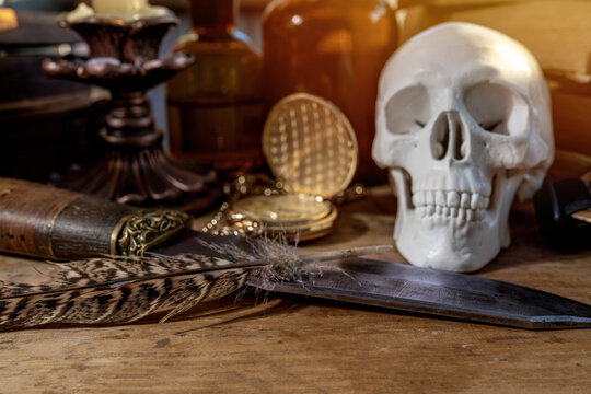 Human skull with a combat knife. The symbol of the head of death with a knife, the candle is a dying life, the clock shows that life is running out