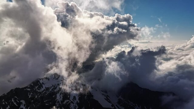Flight in the clouds of vertical development over the mountains during the day. Aerial view between the clouds, horizon-stabilized image from a drone. Time lapse. Weather video background
