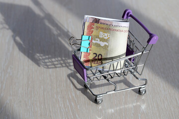 Brazilian money bills in small shopping cart close up