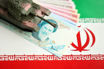Iranian army toy tank drive on iranian bills of rial currency on flag of Islamic Republic of Iran close up