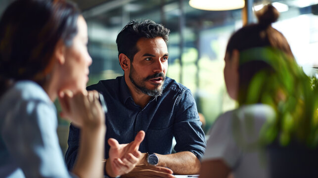 Man gesturing and speaking earnestly to two people during office meeting
