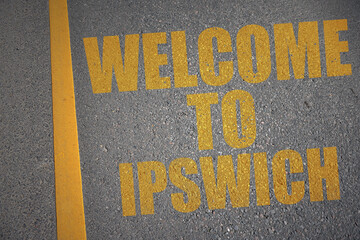 asphalt road with text welcome to Ipswich near yellow line.