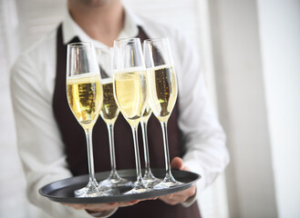 Professional male waiter in uniform serving champagne