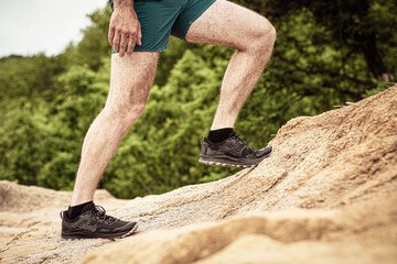 Man runs along a mountain path  closeup feet  sneakers