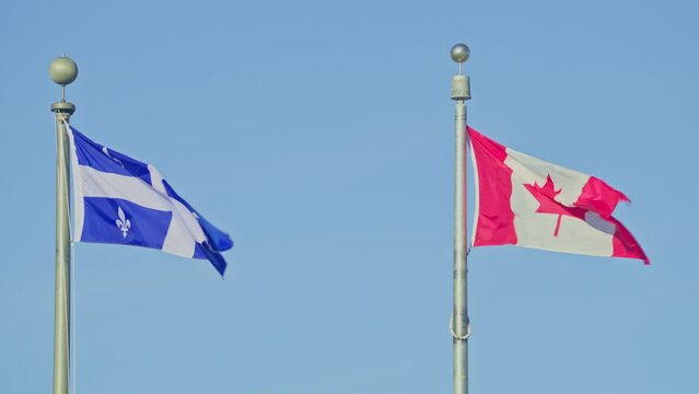 Quebec province flag and Canada country flag together in wind blue sky