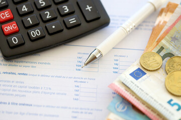 Filling french tax form process with calculator, pen and euro money bills close up. Tax paying...