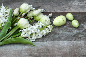 Frohe Ostern! Tulpen, Hyazinthen und Ostereier auf Holzhintergrund mit Platz für Text.