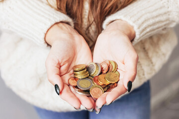 Girl holding money. Female hands full of coins. Woman with money. Metal coins change. Savings in...