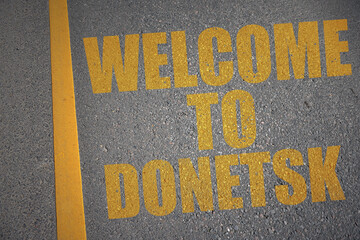 asphalt road with text welcome to Donetsk near yellow line.
