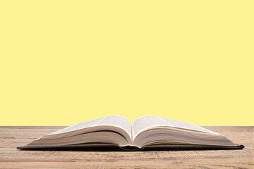 open book. Composition with hardback books, fanned pages on wooden deck table and yellow background. Books stacking. Back to school. Copy Space. Education background.
