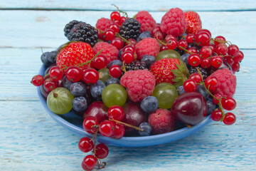 Various summer Fresh berries in a bowl on rustic wooden table. Antioxidants, detox diet, organic fruits.