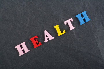 HEALTH word on black board background composed from colorful abc alphabet block wooden letters, copy space for ad text. Learning english concept.