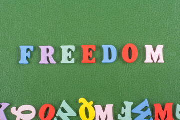 FREEDOM word on green background composed from colorful abc alphabet block wooden letters, copy space for ad text. Learning english concept.
