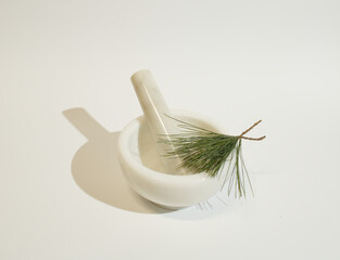 Mortar and pestle with a pine branch on the white background. Minimal concept of natural cosmetics. Flat lay. Copy space.
