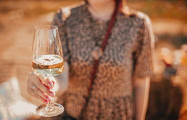 Female in floral dress enjoying white wine on sunny summer day in nature