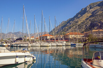 Beautiful Mediterranean landscape. Sailboats in port near Old Town of Kotor on sunny autumn day. Montenegro, Bay of Kotor