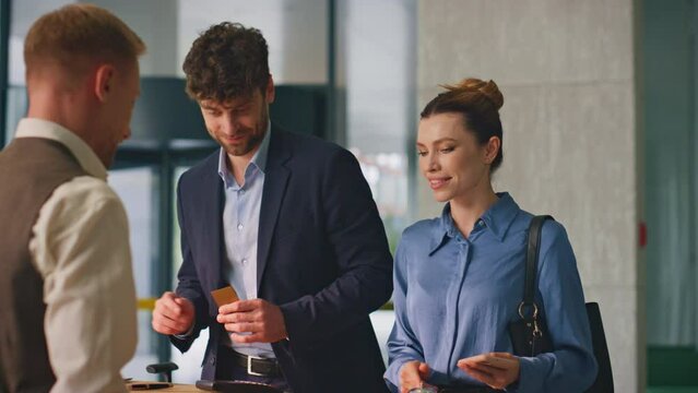 Couple paying hotel reservation with smartphone. Professional concierge assist