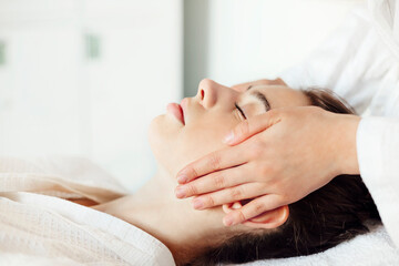 Crop massage therapist massaging face of client