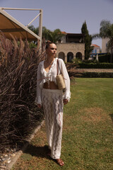 beautiful woman with dark hair in elegant clothes and accessories relaxing in summer beach club