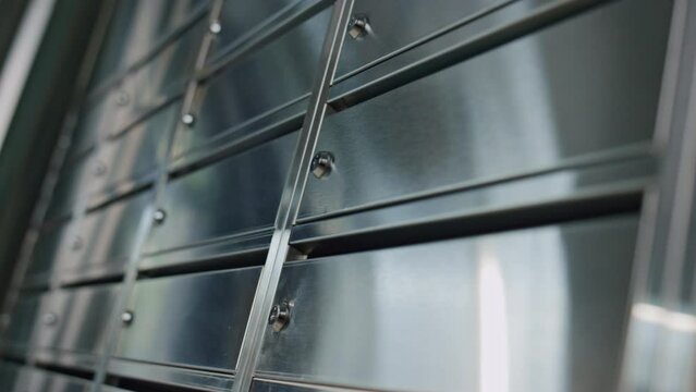 Closeup metal post lockers reflecting light. Closed contemporary mailbox indoors