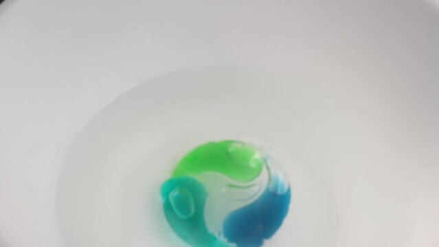 Washing gel capsule pod with laundry detergent to throw into the water. Full frame shots of blue-green liquid laundry detergent pods. selective focus.
