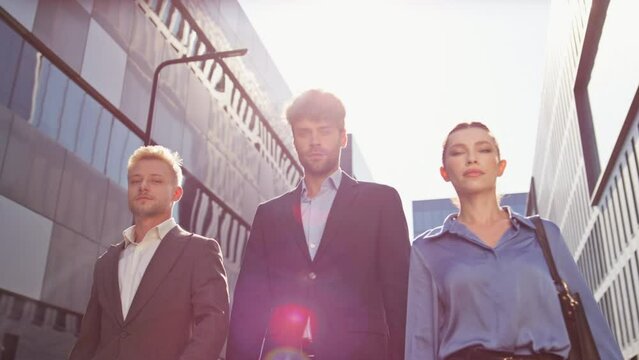 Business team walking together on downtown street. Confident people look camera