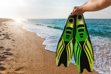 man holds flippers in his hands, against the backdrop of the sea coast. Summer sea holiday in wilderness area for snorkeling © yanik88