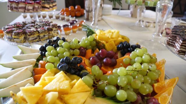 Fruit buffet. Grapes, pineapples, oranges, apples and others. Slow motion.