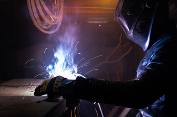 persona working with an electric welding machine. a man in safety glasses and a leather jacket...