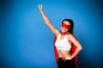 Cheerful woman in superhero cloak holding arm raised