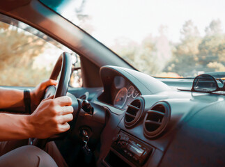A man is driving a car, hands on the steering wheel closeup.