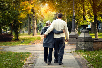 An elderly couple, man and woman walk in the autumn park.