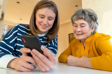 Girl helps her grandmother with mobile phone.