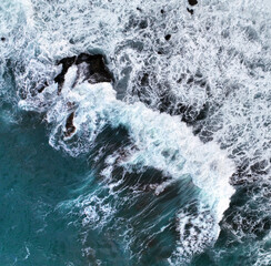 Waves of the Atlantic Ocean, top view from a drone on a turquoise blue water and foam.
