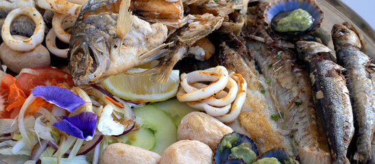 A grilled fish mix plate with various types of fish, seafood, scallops and squid rings.